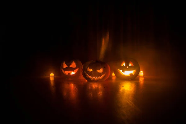 Halloweenská hlava dýňové hlavy a zářící svíčky na pozadí. Dýně na dřevěné podlaze — Stock fotografie