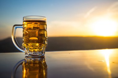 Gün batımında sahilde bir bardak bira. Soğutma yaz içki konsepti. Güneş ışığı Arka Plan Bokeh ile Draught Bira Bir Bardak Close Up