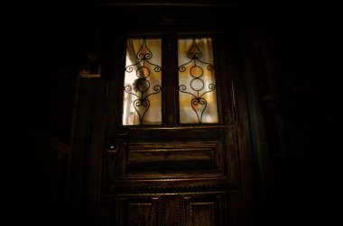 Kapalı bir cam kapıdan eski ahşap bir kapı üzerinde bilinmeyen bir gölge figürü silueti. Geceleri pencerenin önündeki bir insanın silueti.