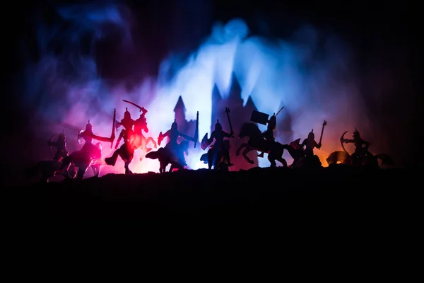 Scena di battaglia medievale con cavalleria e fanteria. Silhouette di figure come oggetti separati, lotta tra guerrieri su sfondo nebbioso dai toni scuri con castello medievale . — Foto Stock