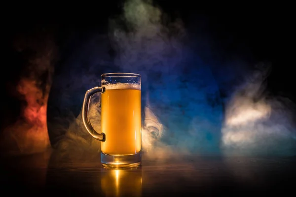 Conceito criativo. copos de cerveja na mesa de madeira no fundo enevoado tonificado escuro . — Fotografia de Stock