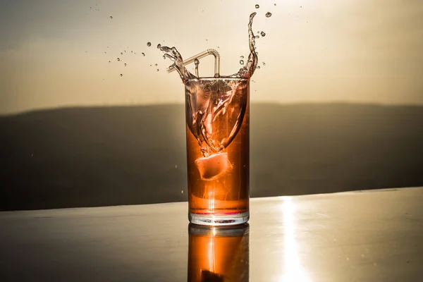 Koncepcja letniego napoju chłodzącego. Kieliszki koktajlowe rozpryskiwania na zachód słońca. Z bliska mokra szklanka zimnego napoju na tarasie. — Zdjęcie stockowe