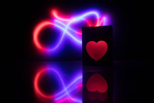 Размытая икона неонового сердца на темном фоне. Копировать пространство с красным ярким красочным сердцем на черном фоне — стоковое фото