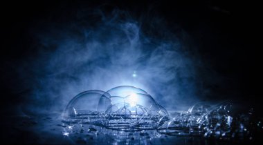 Karanlık bir arka plan üzerinde gökkuşağı sabun kabarcıkları. Sis ve ışık ile soyut ıslak yüzey