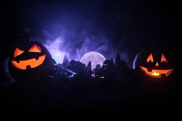 Halloween concept with glowing pumpkins. Strange silhouette in a dark spooky forest at night, mystical landscape surreal lights with creepy man