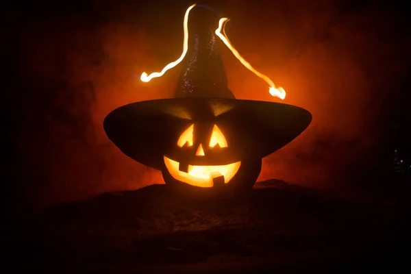 ハロウィーンのコンセプト。パーティーの夜のためのジャック-oランタンの笑顔と怖い目。暗い霧の背景に魔女の帽子をかぶった怖いカボチャのクローズアップビュー。選択フォーカス. — ストック写真