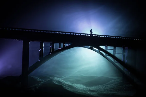 Decoração de obras de arte. Silhueta de ponte metálica poderosa à noite com luz de fundo nebulosa. Silhueta de pessoa de pé na ponte . — Fotografia de Stock