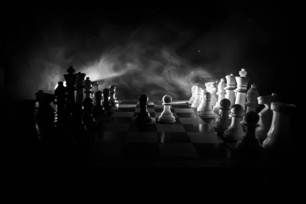 Sakktábla játék fogalmát az üzleti ötletek és a versenyt. Sakkfigurák egy sötét háttéren füsttel és ködvel. — Stock Fotó
