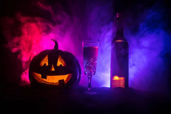 Due bicchieri di vino e bottiglia con Halloween - vecchio jack-o-lanterna su sfondo scuro tonica nebbiosa. Zucca spaventosa di Halloween — Foto Stock