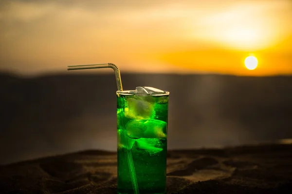 Close up wet glass of green cold mint drink, colorful orange sunset background on the terrace. Cooling summer drink. Summer fresh and cooling inspiration, evening contrast color combination. — Stock Photo, Image