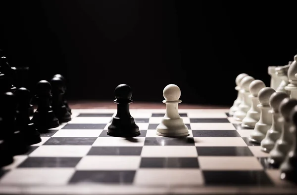 Sakktábla játék fogalmát az üzleti ötletek és a versenyt. Sakkfigurák egy sötét háttéren füsttel és ködvel. — Stock Fotó