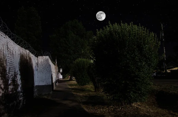 Lua cheia sobre bastante aldeia à noite. Bela paisagem noturna da rua da cidade velha com luzes. Rússia — Fotografia de Stock