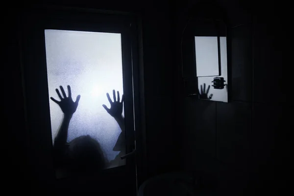 Horror silhouette of woman in window. Scary halloween concept Blurred silhouette of witch in bathroom. Selective focus