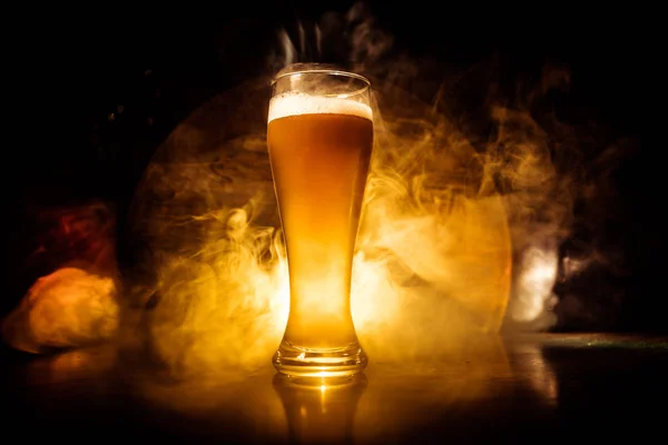 Δημιουργική ιδέα. Ποτήρια μπύρας σε ξύλινο τραπέζι σε σκούρο τονισμένο φόντο. — Φωτογραφία Αρχείου