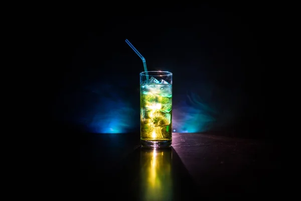 Склянка коктейлю розбризкується на темному тонованому димчастому фоні або барвистому коктейлі в склі. Вечірній клуб розваг. Змішане світло . — стокове фото