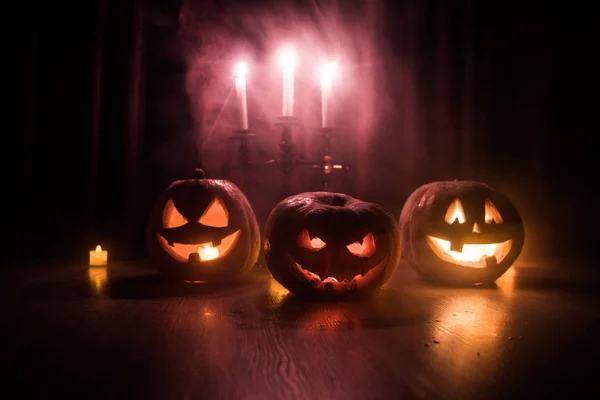 Cabeza de calabaza de Halloween jack o linterna con velas brillantes en el fondo. Calabazas en suelo de madera —  Fotos de Stock