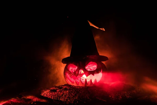 Halloween concept. Jack-o-lantern glimlach en enge ogen voor feest avond. Close-up weergave van enge pompoen met Witch hat op donkere mistige achtergrond. Selectieve focus. — Stockfoto