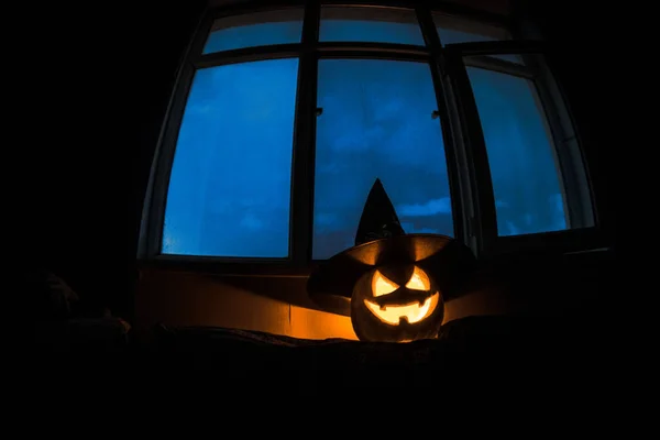 Scary Απόκριες κολοκύθας στο παράθυρο μυστικιστική σπίτι στο βράδυ ή Απόκριες κολοκύθας νύχτα στο δωμάτιο με μπλε παράθυρο. Σύμβολο αποκριών στο παράθυρο. — Φωτογραφία Αρχείου