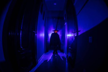 Cadılar Bayramı konsepti. Balkabağı başlı karanlık koridorda ürpertici siluet. Arka planda sis olan tonlu ışık. Seçici odaklama