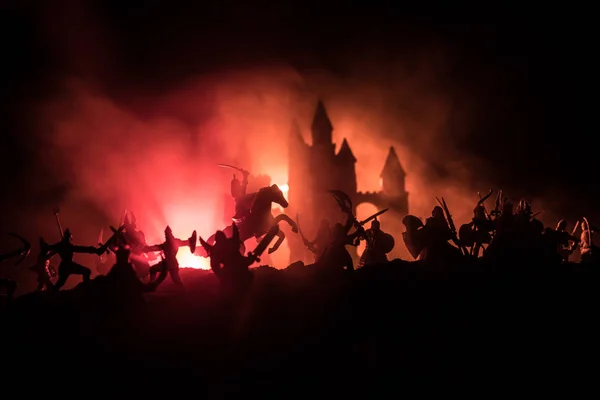 Μεσαιωνική σκηνή μάχης με ιππικό και πεζικό. Σιλουέτες των αριθμητικών στοιχείων ως ξεχωριστά αντικείμενα, πάλη μεταξύ των πολεμιστών σε σκοτεινή ήπια ομίχλη φόντο με μεσαιωνικό κάστρο. — Φωτογραφία Αρχείου