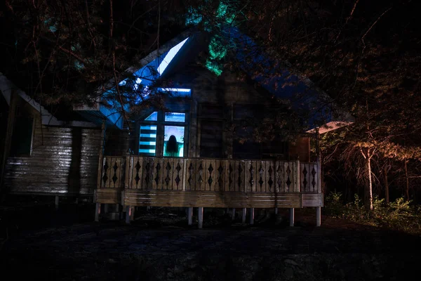 Oud huis met een geest in het bos 's nachts of verlaten spookhuis in mist. Oud mystiek gebouw in dood boombos. Bomen 's nachts met de maan. Surrealistische lichten. Horror Halloween concept — Stockfoto