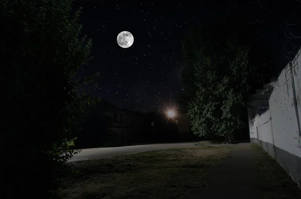Luna llena sobre un pueblo tranquilo por la noche. Hermoso paisaje nocturno de la calle del casco antiguo con luces. Rusia —  Fotos de Stock