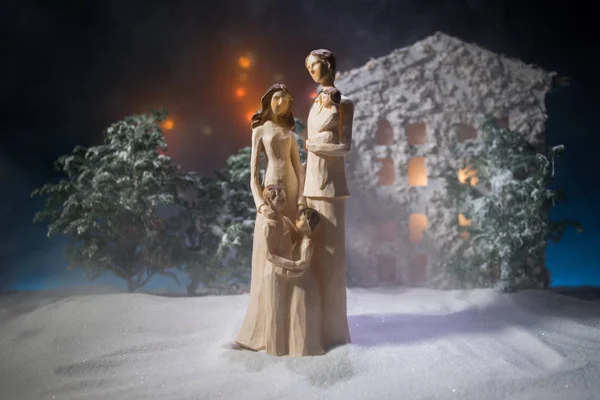 Bonne année, jeune famille de trois personnes debout dans la cour de devant, regardant dans le ciel le soir ? Maison décorée avec des guirlandes pour la veille de Noël . — Photo