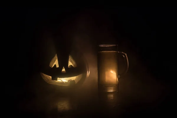 Bicchiere di birra leggera fredda con zucca su uno sfondo di legno per Halloween. Bicchiere di birra fresca e zucca su uno sfondo scuro tonico nebbioso — Foto Stock