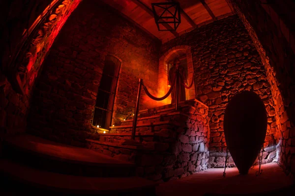 Inside of old creepy abandoned mansion. Staircase and colonnade. Silhouette of horror ghost standing on castle stairs to the basement. Spooky dungeon stone stairs in old castle with light.