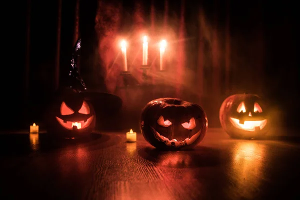 Halloween pompoen hoofd Jack o lantaarn met gloeiende kaarsen op achtergrond. Pompoenen op houten vloer — Stockfoto