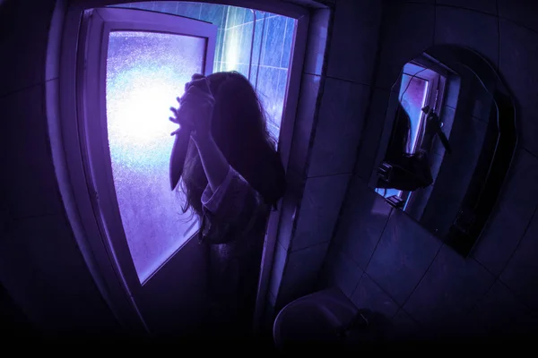 Horror silhouette of woman in window. Scary halloween concept Blurred silhouette of witch in bathroom. Selective focus