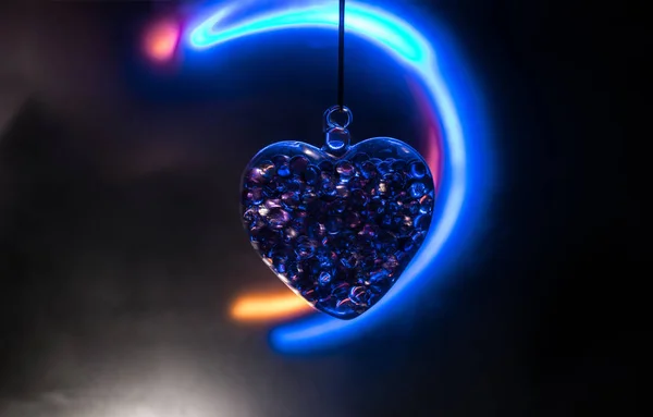 Concepto del Día de San Valentín. Corazón transparente de cristal en la oscuridad. Corazón de cristal en la oscuridad, el corazón de vidrio brilla, pintura de vidrio, fondo negro — Foto de Stock