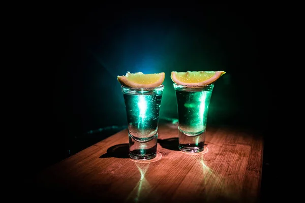 Concepto de bebida del club. Bebida alcohólica sabrosa cóctel de tequila con lima y sal sobre fondo oscuro vibrante o vasos con tequila en un bar — Foto de Stock