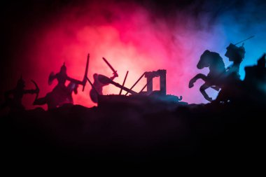 Süvari ve piyade ile Ortaçağ savaş sahnesi. Ayrı nesneler olarak figürlerin siluetleri, ortaçağ kalesi ile karanlık tonda sisli arka plan üzerinde savaşçılar arasında mücadele.