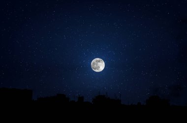 Büyük bir ay arka plan ile karanlık şehirde gökdelenler farklı inşaat siluetleri