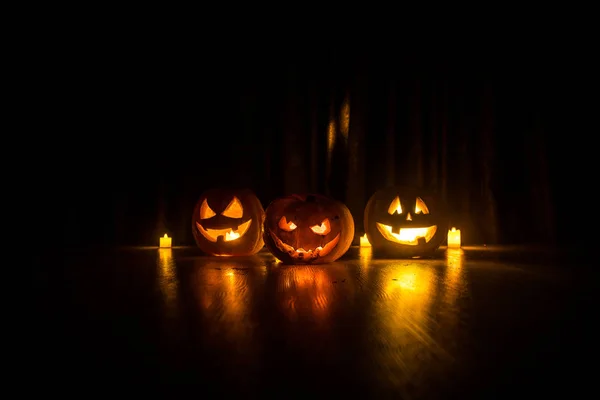 Halloween zucca testa jack o lanterna con candele incandescenti su sfondo. Zucche sul pavimento in legno — Foto Stock