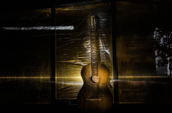 나무어쿠스틱 기타는 그런지 질감의 벽에 대항합니다. 방은 카피 스페이스에 대한 스포트 라이트와 어두운. — 스톡 사진