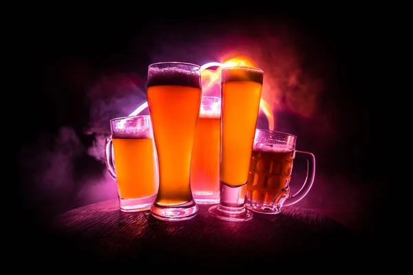 Concepto creativo. Vasos de cerveza sobre mesa de madera en fondo nebuloso tonificado oscuro . — Foto de Stock