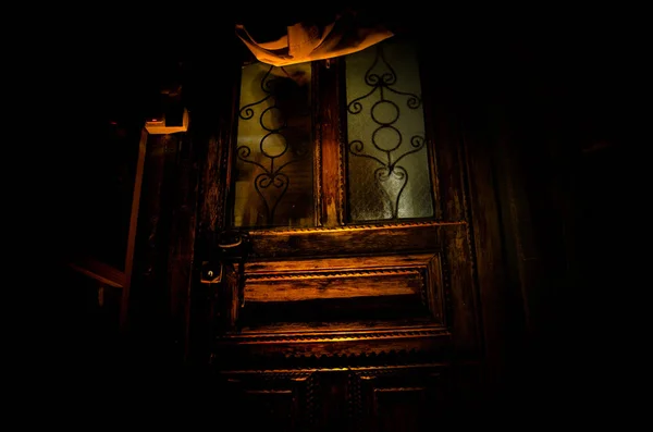 Silhouette of an unknown shadow figure on a old wooden door through a closed glass door. The silhouette of a human in front of a window at night. — Stock Photo, Image