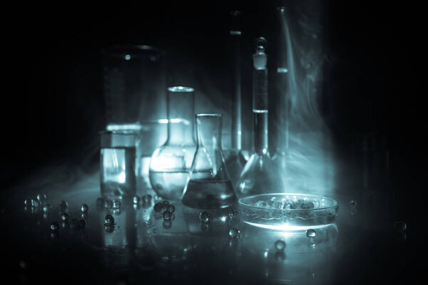 Pharmacy and chemistry theme. Test glass flask with solution in research laboratory. Science and medical background. Laboratory test tubes on dark toned background