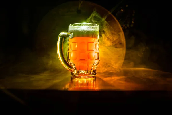 Conceito criativo. copos de cerveja na mesa de madeira no fundo enevoado tonificado escuro . — Fotografia de Stock