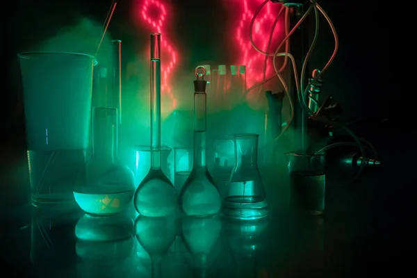 Téma lékárny a chemie. Zkušební skleněná baňka s roztokem ve výzkumné laboratoři. Věda a lékařské zázemí. Laboratorní zkumavky na tmavě tonované pozadí — Stock fotografie