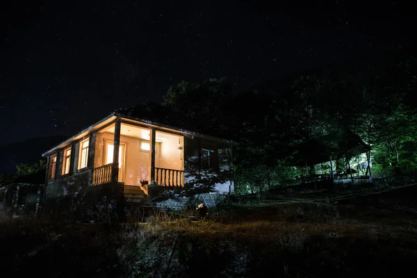 Gammalt hus med en Ghost i skogen på natten eller Övergiven Haunted Horror House i dimma. Gammal mystisk byggnad i död trädskog. Träd på natten med månen. Surrealistiska ljus. Halloween-konceptet — Stockfoto