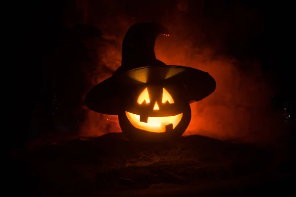 Concept d'Halloween. Jack-o-lanterne sourire et les yeux effrayants pour la soirée. Vue rapprochée de citrouille effrayant avec chapeau de sorcière sur fond sombre brumeux. Concentration sélective . — Photo