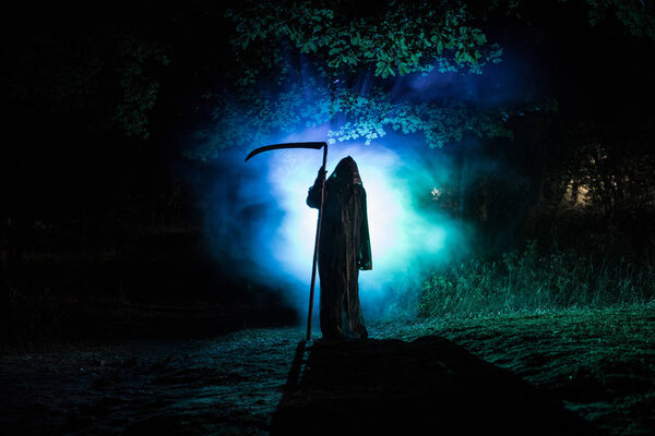 Death with a scythe in the dark misty forest. Woman horror ghost holding reaper in forest