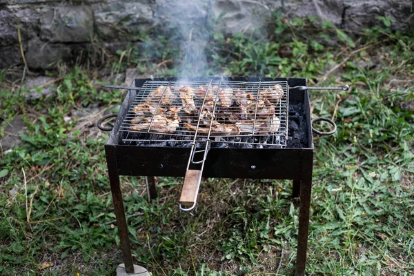 Grilovaný kebab na kovové špejli. Pečené maso vařené na grilu.Tradiční východní pokrm, shish kebab. Gril na dřevěném uhlí a plameni, piknik, pouliční jídlo — Stock fotografie
