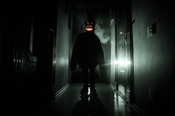 Halloween concept. Griezelig silhouet in de donkere gang met pompoen hoofd. Licht getint met mist op de achtergrond. Selectieve focus — Stockfoto