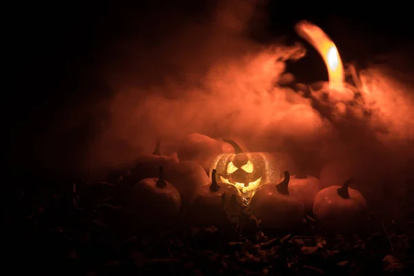 Halloween jack-o-lantern on autumn leaves. Scary Halloween Pumpkin looking through the smoke. Glowing, — Stock Photo, Image