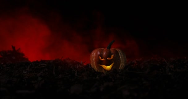 Хэллоуин Джек-о-фонарь на осенних листьях. Страшная тыква на Хэллоуин смотрит сквозь дым. Светящийся , — стоковое видео