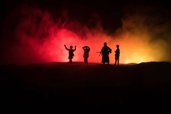 Battle scene. Military silhouettes fighting scene on war fog sky background. A German soldiers raised arms to surrender. Plastic toy soldiers with guns taking prisoner the enemy soldier. — Stock Photo, Image